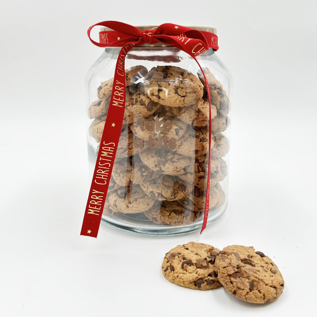 Glazen pot gevuld met chocoladekoekjes met Merry Christmas lint