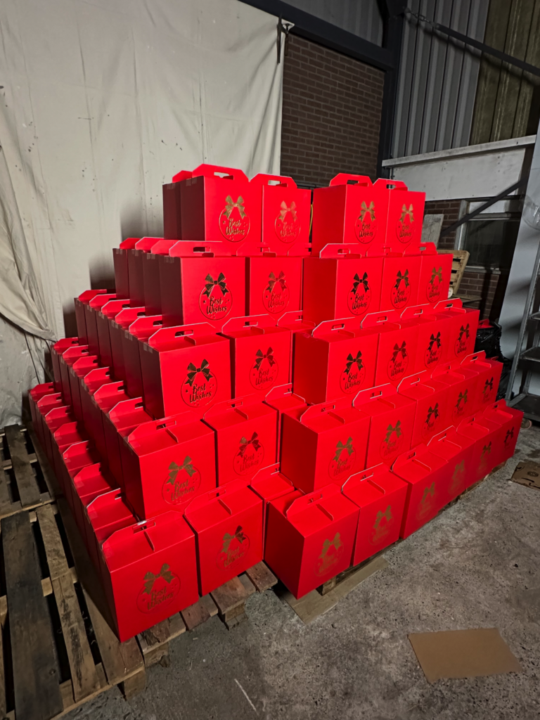 Grote stapel rode geschenkdozen met Best Wishes opdruk in het magazijn